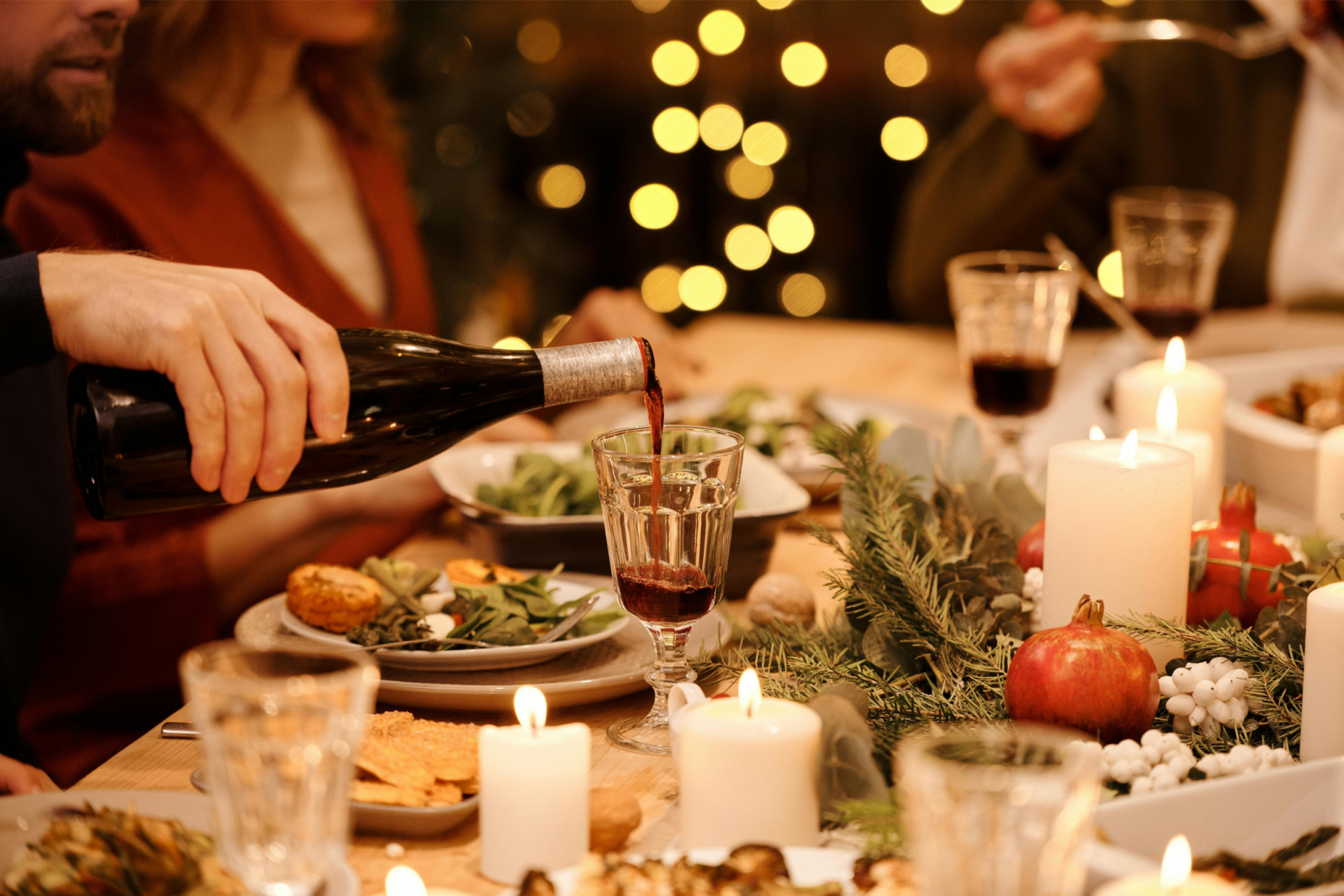 A person pouring red wine in a glass during christmas dinner